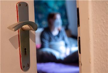 Ein Mensch sitzt während der Isolation nach einem positiven Corona-PCR-Test auf ihrem Bett.