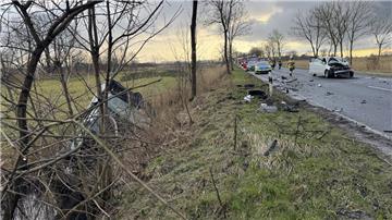 Ein zerstörtes Auto liegt in einem Graben. Auf der Straße steht ein weiteres zerstörtes Auto.