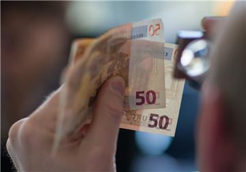 Ein Mitarbeiter des Nationalen Analysezentrums der Deutschen Bundesbank prüft mit der Lupe zwei 50 Euro-Banknoten. Geldfälscher produzieren häufig 50- und 20-Euro-Blüten.