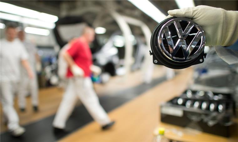 Streit mit Zulieferern: VW setzt Golf-Produktion im Stammwerk aus Ein Mitarbeiter hält ein Volkswagen-Logo im VW-Werk in Wolfsburg (Niedersachsen) an der Produktionsstraße für den VW Golf VII.