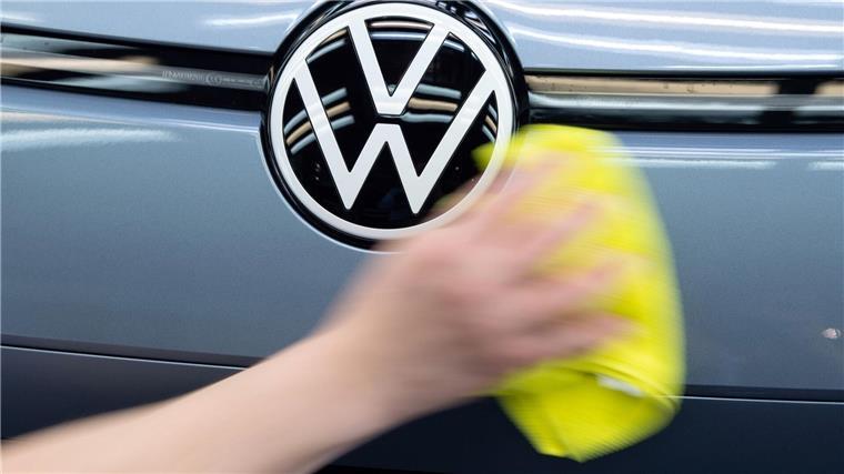 Fehlende Elektromotoren: VW drosselt Produktion in Emden Ein Mitarbeiter von Volkswagen streicht mit einem Tuch über ein Fahrzeug von VW.