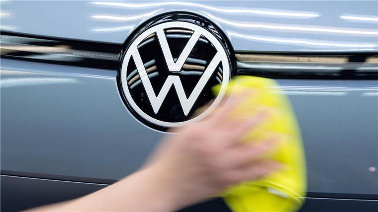 VW will auch bei Investitionen sparen Ein Mitarbeiter von Volkswagen streicht mit einem Tuch über ein Fahrzeug von VW.