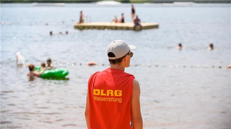 Schwierige Strömungsverhältnisse: DLRG warnt vor Gefahren Ein Mitglied der Deutschen Lebens-Rettungs-Gesellschaft (DLRG) steht in einem Strandbad am Ufer.