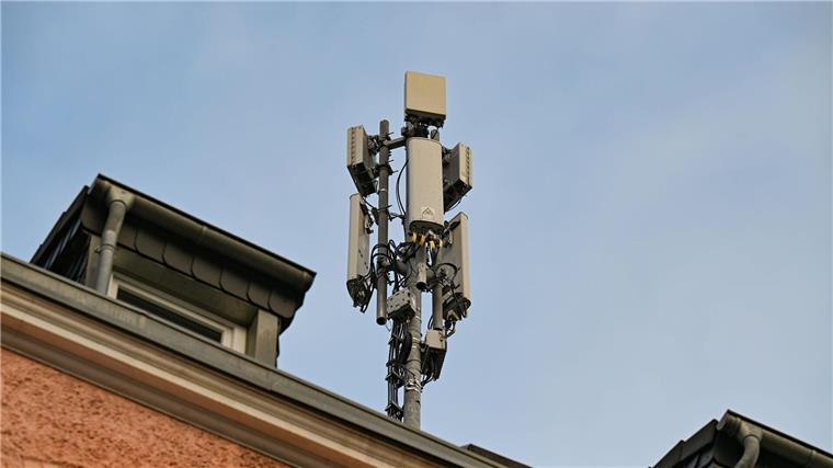 Ein Mobilfunkmast mit 4G/LTE-Antennen (länglich) und 5G-Antennen (quadratisch) steht auf einem Dach eines Wohnhauses.