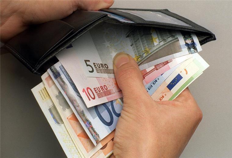 Ein Mann verstaut einige Euro-Geldscheine in seiner Geldbörse.