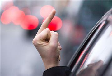 Ein Mann streckt seinen Mittelfinger aus der Seitenscheibe eines Fahrzeuges.