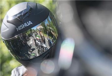 Motorradfahrer spiegeln sich in einem Motorradhelm.