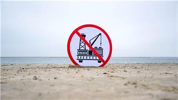 Ein Plakat gegen die geplante Erdgasförderung steht im Sand.