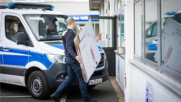 Ein Polizeibeamter geht während einer Durchsuchung an einem Polizeiwagen vorbei.