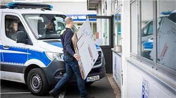 Ein Polizeibeamter geht während einer Durchsuchung an einem Polizeiwagen vorbei.
