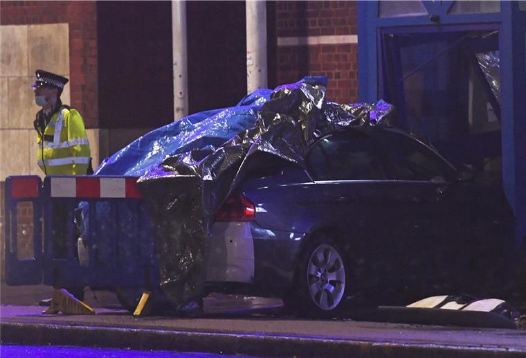 London: Auto fährt in Polizeiwache - Terrorattacke? Ein Polizist steht neben einem Auto am Tatort des Polizeireviers von Edmonton (London). Ermittler haben im Norden von London einen Mann festgenommen, nachdem ein Auto in eine Polizeiwache gefahren war.