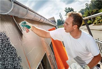 Handwerker arbeitet an Hausfassade