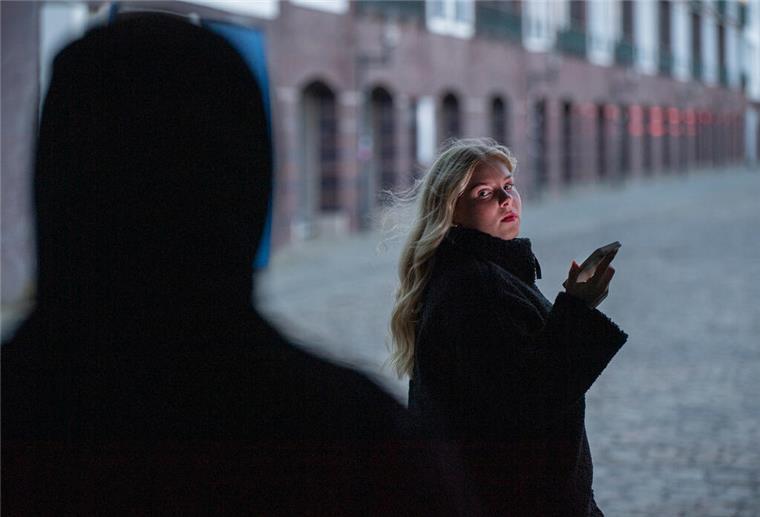 Frau mit Handy und dunkle Gestalt