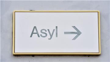 Ein Schild mit der Aufschrift „Asyl“ hängt an einer Wand.