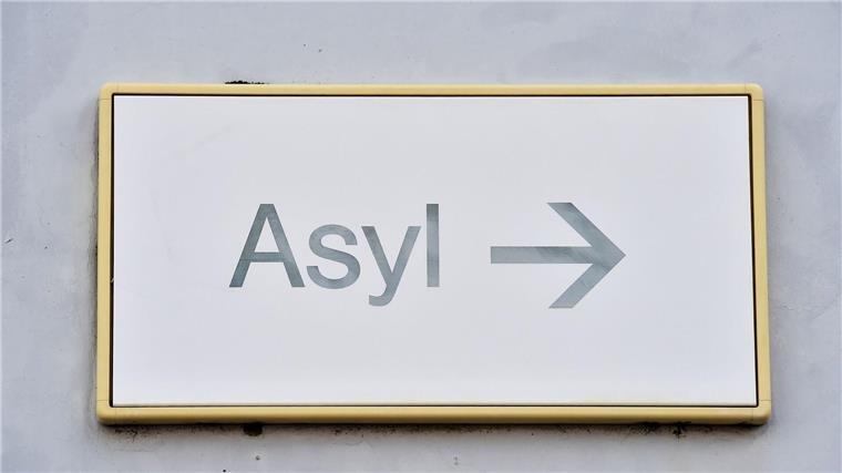 Ein Schild mit der Aufschrift „Asyl“ hängt an einer Wand.