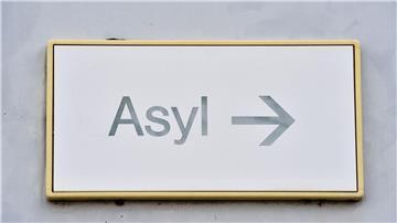 Ein Schild mit der Aufschrift „Asyl“ hängt an einer Wand.