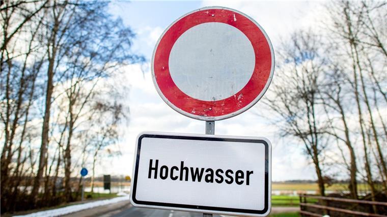 Ein Schild mit der Aufschrift „Hochwasser“ steht vor einer gesperrten Straße.