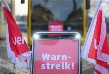 Ein Schild „Warnstreik“ steht vor einem Bus.