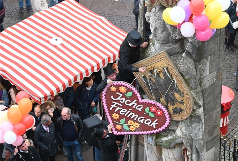 Ein Schornsteinfeger hängen dem Bremer Roland ein Lebkuchenherz um.
