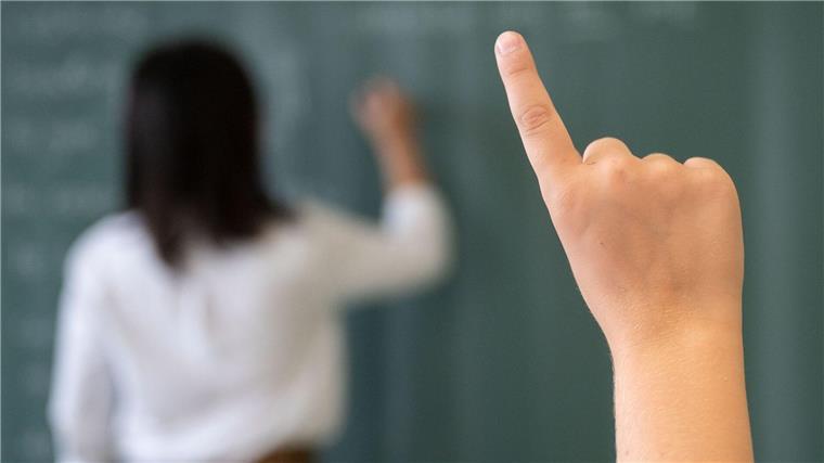 Schwangere dürfen wieder in Präsenz unterrichten Ein Schüler meldet sich, während die Lehrerin an die Tafel schreibt.