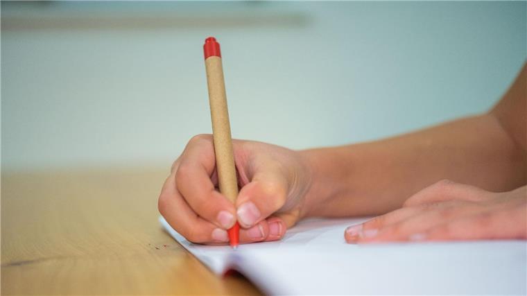 Ministerin: Startchancen-Programm für Bildungsgerechtigkeit Ein Schüler schreibt mit einem Kugelschreiber in sein Heft.