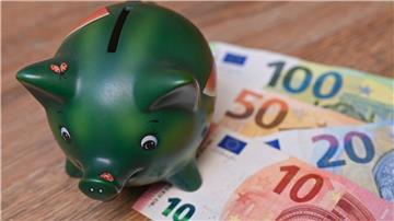 Ein Sparschwein steht auf einem Tisch neben Eurobanknoten.