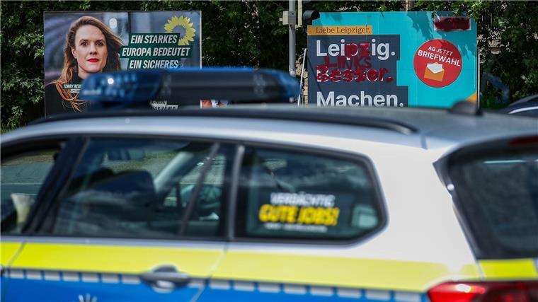 Ein Streifenwagen der Polizei fährt an Wahlplakaten vorbei.