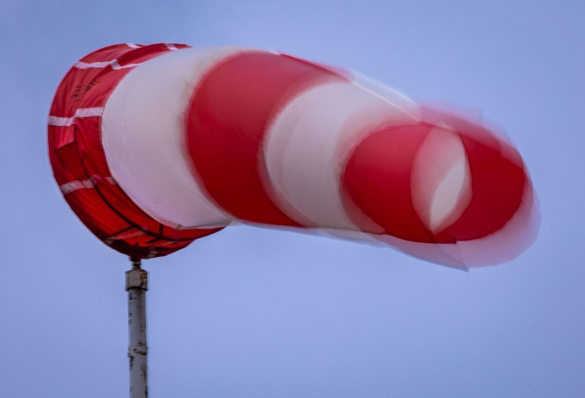 Ein Windsack weht bei Regen bei kräftigem Wind am Mast. 