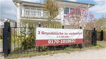Ein Transparent mit der Aufschrift „3 Grundstücke zu verkaufen! €3.500.000“ hängt an einem Grundstück.