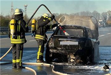 Feuerwehrleute löschen ein Auto auf der Autobahn