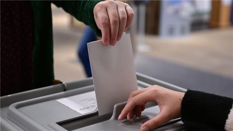Bremen: Rekord bei Wahlberechtigten mit Migrationsgeschichte Ein Wähler steckt seinen Wahlzettel in eine Urne.