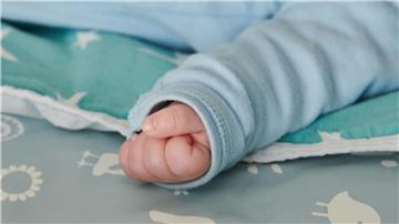 Ein wenige Wochen altes Baby ballt seine Hand zu einer kleinen Faust.