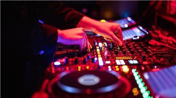 Ein DJ steht in einem Club am Mischpult.