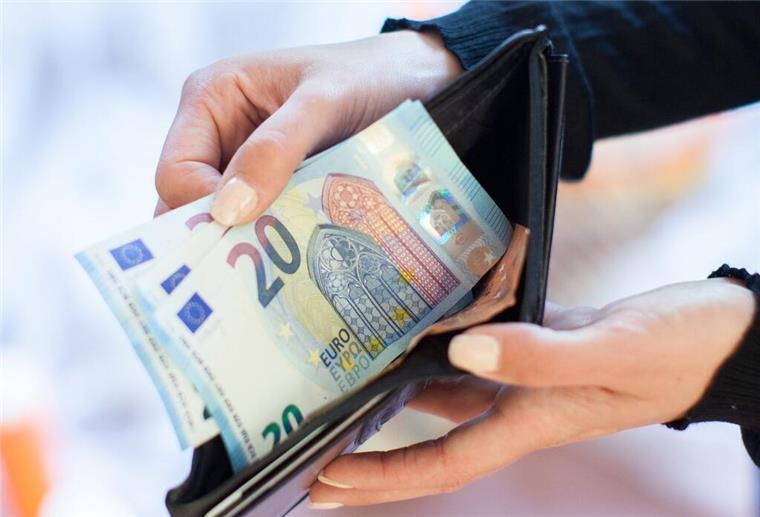 Eine Person hält 20-Euro-Scheine aus ihrer Geldbörse in die Kamera. 
