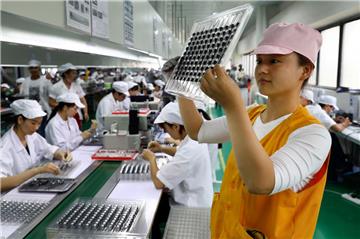 Eine Arbeiterin inspiziert die Mikromotoren für Handys in einer High-Tech-Fabrik in China.
