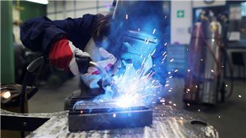 Eine Auszubildende zur Schweißerin arbeitet an einem Stück Metall.