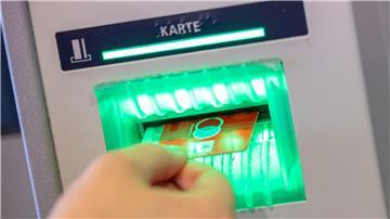 Eine Bankkundin steckt ihre Girokarte in einen Geldautomaten.