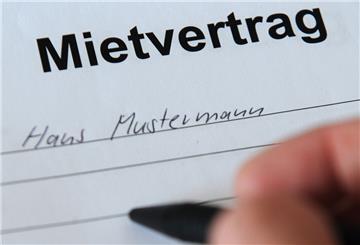 Eine Hand schreibt auf einen Mietvertrag,