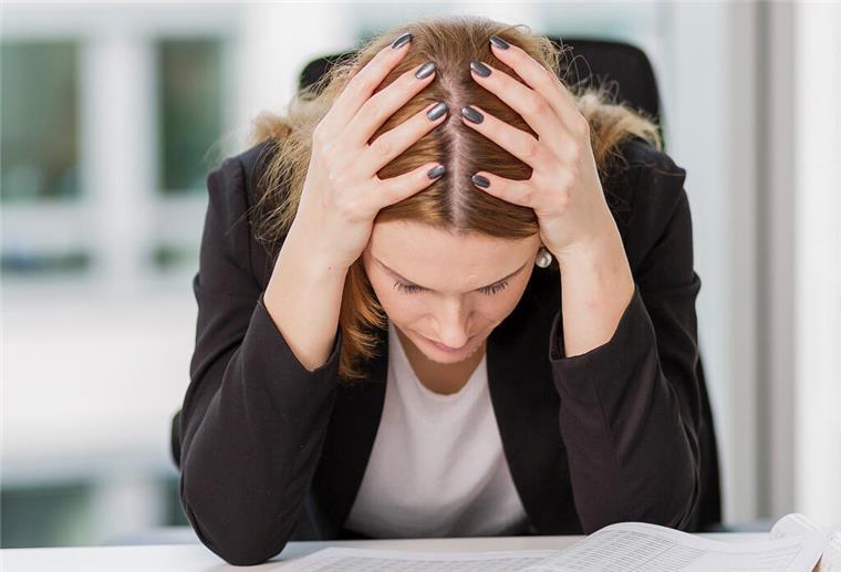 Du willst weniger arbeiten? So sagst Du es Deinem Chef Eine Frau hält den Kopf in ihren Händen