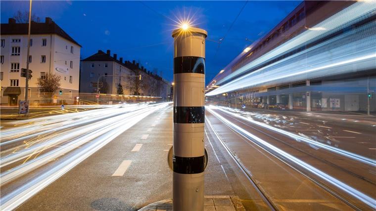 Verfassungsbeschwerden zu Rohmessdaten erfolglos Eine Blitzsäule mit kombinierter Überwachung von Rotlicht und Geschwindigkeit steht an einer Ampelkreuzung (Langzeitbelichtung).