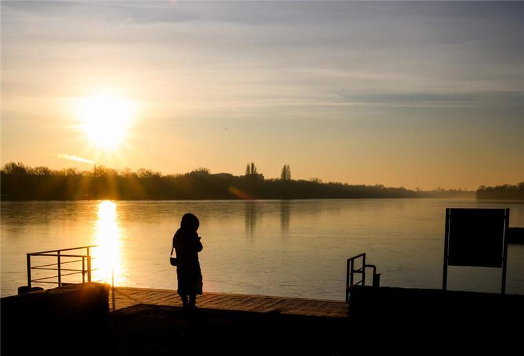 Morgens glücklich, abends gestresst: Wie die Tageszeit unsere Stimmung prägt 03.02.2025, Niedersachsen, Hannover: Eine Frau steht bei Sonnenaufgang am gefrorenen Maschsee. Foto: Julian Stratenschulte/dpa +++ dpa-Bildfunk +++