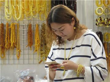 Eine chinesische Besucherin steht an einem Messestand auf der Internationalen Messe für Bernstein, Schmuck und Steine (AMBERIF)  in Danzig, Polen. 
