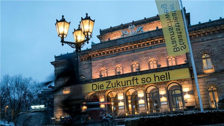 Eine dünne Schneedecke liegt am Morgen vor dem Staatstheater, an dem ein Banner mit der Aufschrift „Die Zukunft so hell“ hängt.