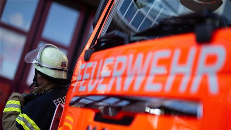 Eine Einsatzkraft der Feuerwehr steht neben einem Einsatzfahrzeug der Feuerwehr.