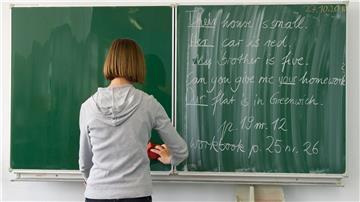 Eine Englisch-Lehrerin einer Grundschule wischt die Tafel ab.