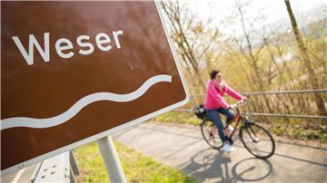Eine Fahrradfahrerin fährt auf dem Weser-Radweg.