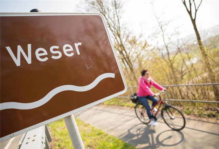 Eine Fahrradfahrerin fährt auf dem Weser-Radweg.