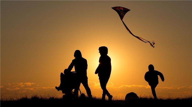 Pflegeeltern sollen elterngeldähnliche Zahlung bekommen Eine Familie geht bei Sonnenuntergang über einen Weg.