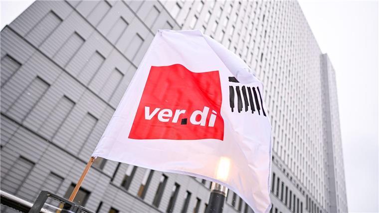 Busse und Straßenbahnen sollen im Warnstreik stillstehen Eine Flagge von Verdi weht bei einem Warnstreik vor einem Hochhaus.