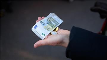 Eine Frau hält das Bargeld für ihren Einkauf in der Hand bereit.